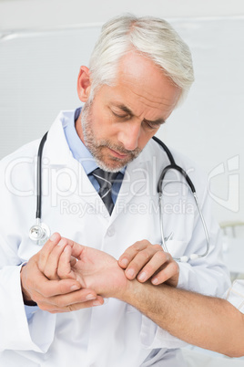 Male doctor taking a patients pulse