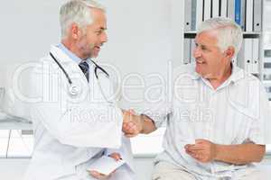 Smiling senior patient and doctor shaking hands