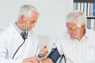 Doctor taking the blood pressure of his retired patient