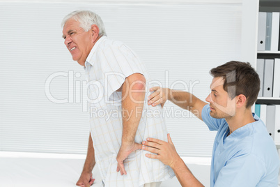 Male physiotherapist examining senior mans back