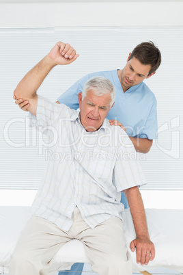 Mhysiotherapist assisting senior man to raise hand