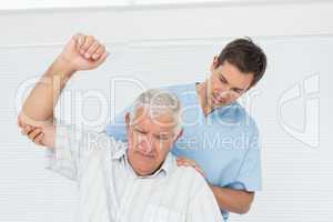 Male physiotherapist assisting senior man to raise hand