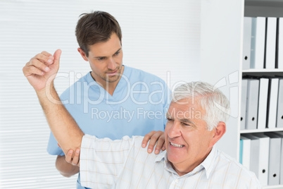 Physiotherapist assisting senior man to stretch his hand