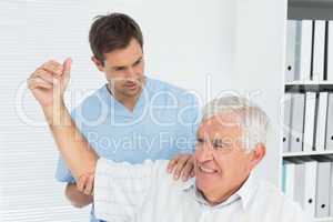 Physiotherapist assisting senior man to stretch his hand