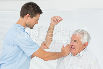 Physiotherapist assisting senior man to stretch his hand