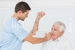 Physiotherapist assisting senior man to stretch his hand