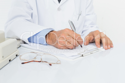 Mid section of a male doctor writing reports