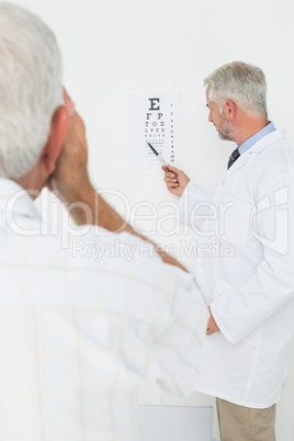 Pediatrician ophthalmologist with senior patient pointing at eye