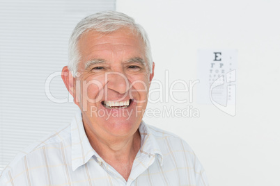 Smiling senior man with eye chart in the background