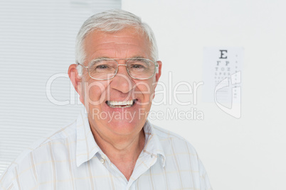 Portrait of a smiling senior man with eye chart in background