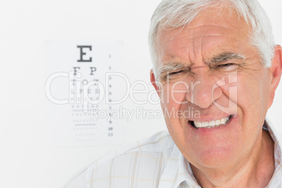 Portrait of a senior man with eye chart in background