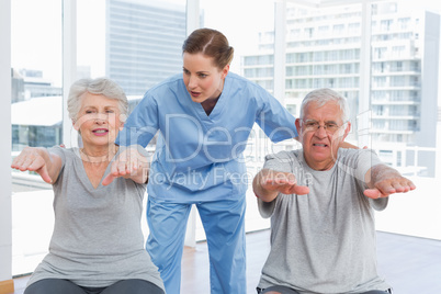 Female therapist assisting senior couple with exercises