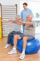 Female therapist assisting senior couple with exercises