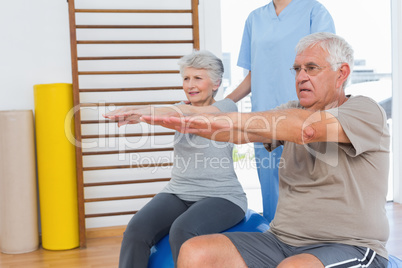 Therapist assisting senior couple with exercises