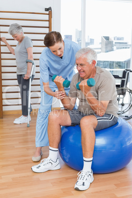 Therapist assisting senior man with dumbbells