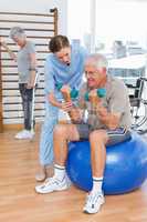 Therapist assisting senior man with dumbbells