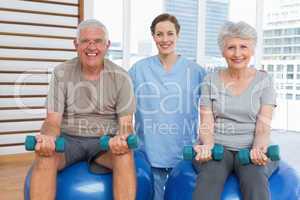 Female therapist assisting senior couple with dumbbells