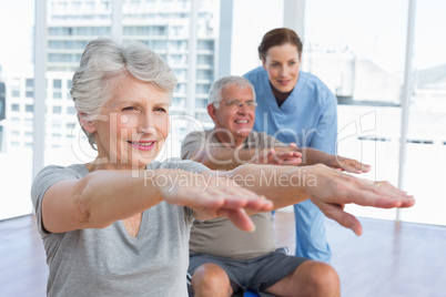 Female therapist assisting senior couple with exercises