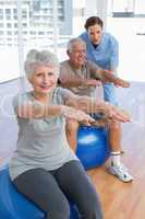 Female therapist assisting senior couple with exercises