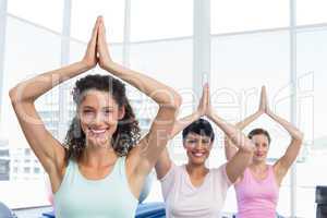 Sporty women with joined hands over head at fitness studio