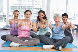 Women gesturing thumbs up in yoga class