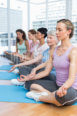 Women in lotus pose with eyes closed at fitness studio