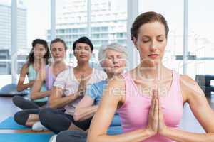 Class sitting with joined hands in row at yoga class