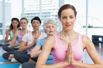 Class sitting with joined hands in row at yoga class