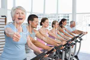 Woman gesturing thumbs up with class at spinning class