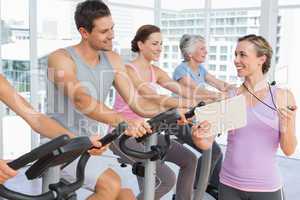 Trainer besides people working out at spinning class