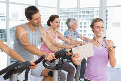 Trainer besides people working out at spinning class