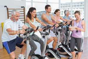 Trainer besides people working out at spinning class