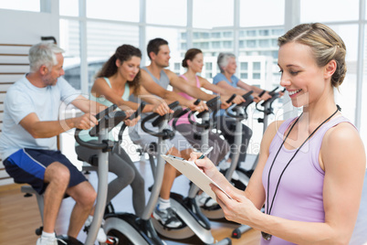 Trainer with people working out at spinning class