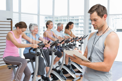 Trainer with people working out at spinning class