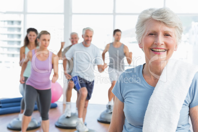 Senior woman with people exercising in fitness studio