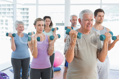 Class exercising with dumbbells in gym