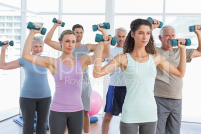 Class exercising with dumbbells in gym