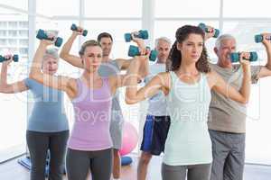 Class exercising with dumbbells in gym