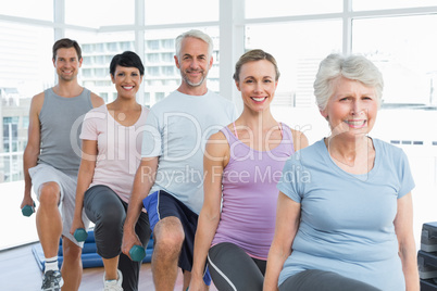 Class exercising with dumbbells in gym