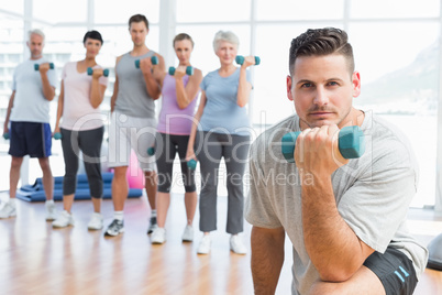 Class exercising with dumbbells in gym