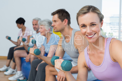 Class exercising with dumbbells in gym