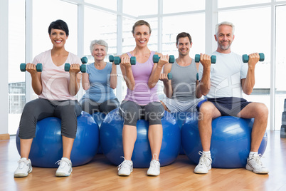 Fitness class with dumbbells sitting on exercise balls