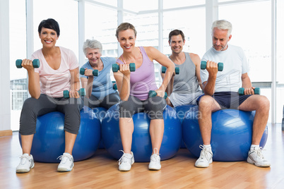 Fitness class with dumbbells sitting on exercise balls