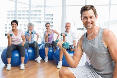 Fitness class with dumbbells sitting on exercise balls