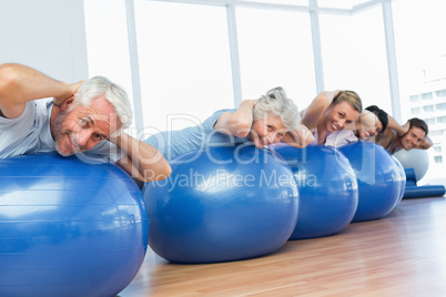 Sporty people stretching on exercise balls in gym