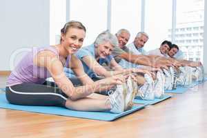 Class stretching hands to legs at yoga class