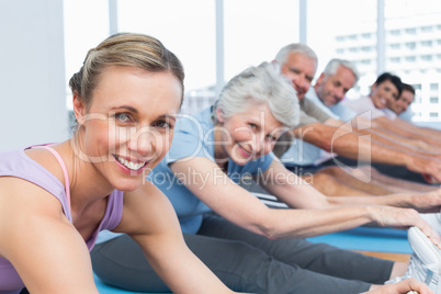 Class stretching hands to legs at yoga class