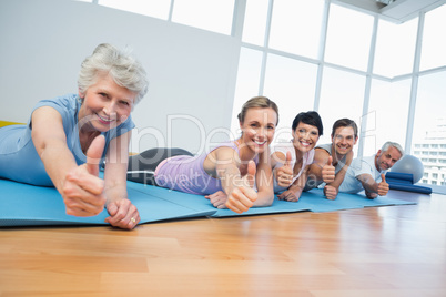 Fitness group gesturing thumbs up at yoga class