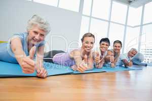 Fitness group gesturing thumbs up at yoga class