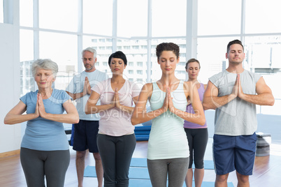 People with eyes closed and joined hands at fitness studio